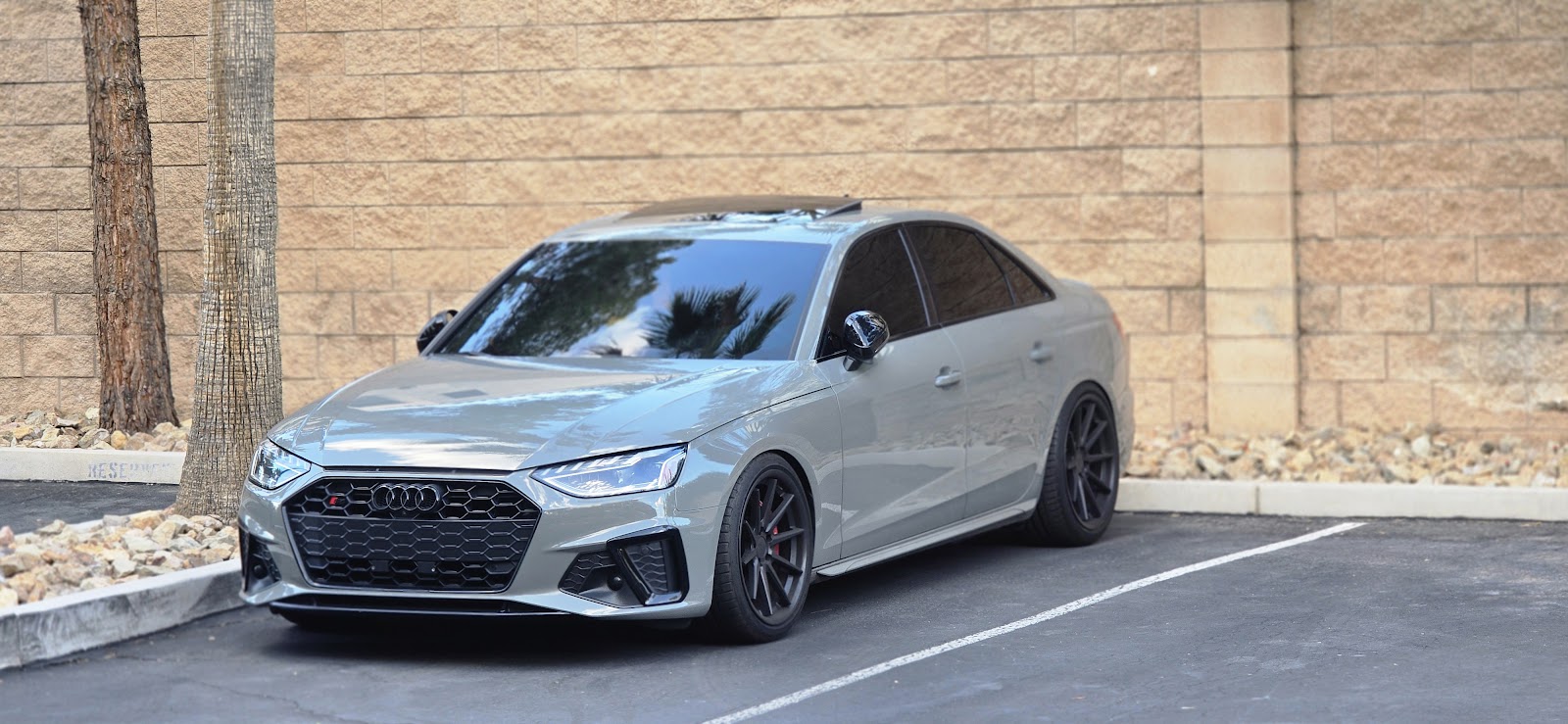 Nardo gray Audi S4 with tinted windows against a block wall