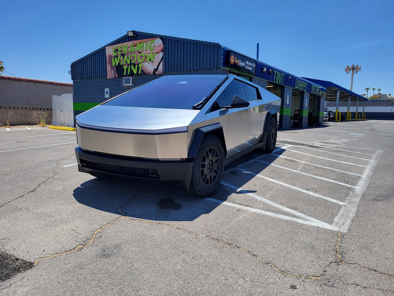 Tesla Cybertruck parked in front of the shop beside a Ceramic Window Tint sign