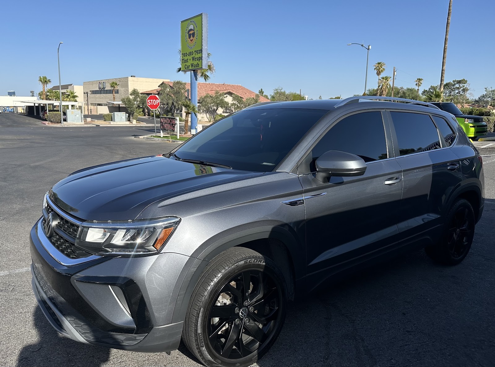 Gray VW Taos SUV with tinted windows and a shop pole sign in the background