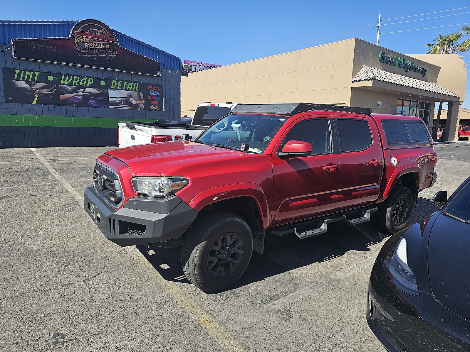 Red Toyota Tacoma outside Fresh & Clean Carwash with a Tint Wrap Detail banner